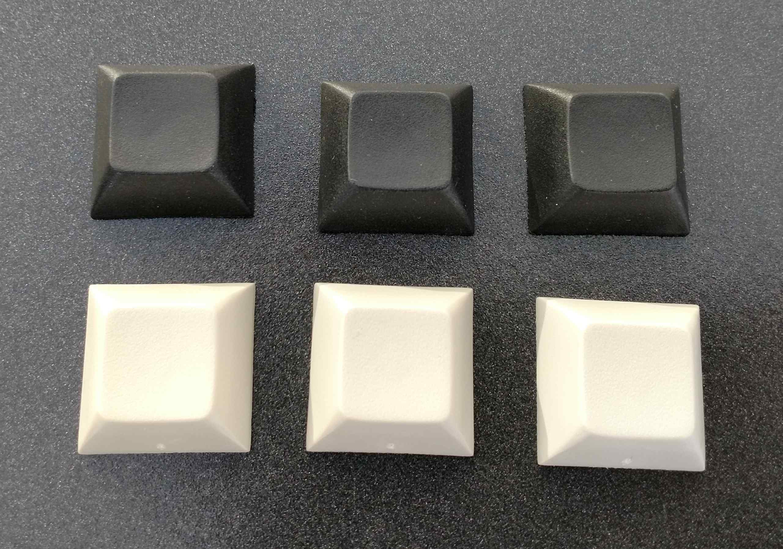 DSA keycaps in black and beige. The beige ones have minor molding imperfections on their sides. Like little braille dots.
